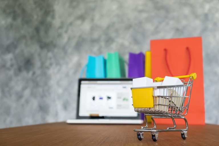 Miniature d’un e-commerce en refonte: un chariot de shopping devant un ordinateur portable et des sacs colorés, illustration d’une refonte site e-commerce prestashop.