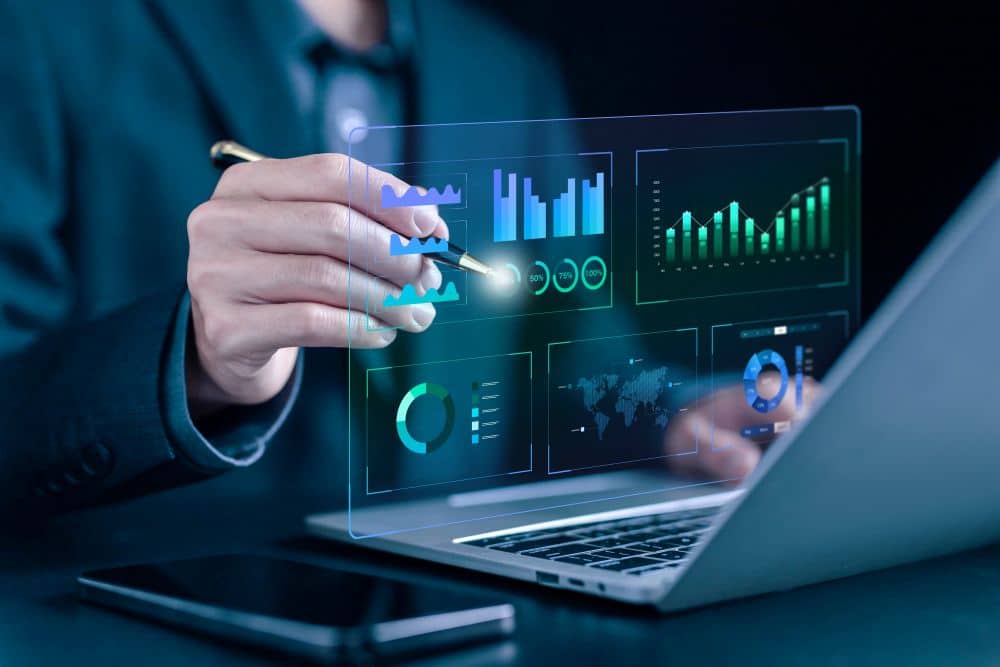Consultant analysant des données et graphiques sur un écran transparent, près d’un ordinateur portable, pour choisir les mots clés seo comment choisir.