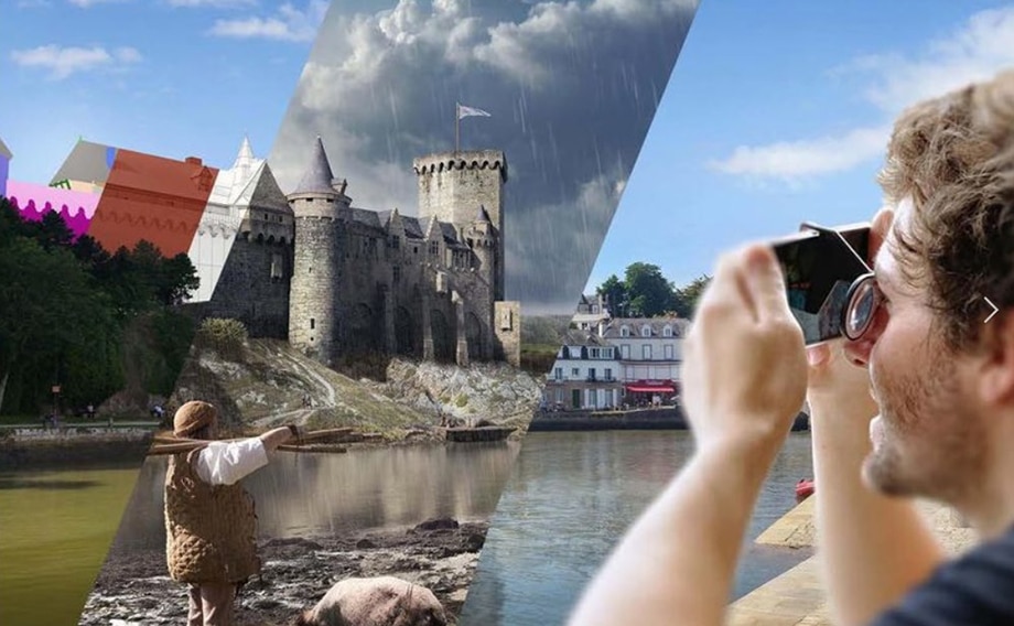 Une personne prend une photo avec un appareil photo, devant un paysage mêlant château et ville.