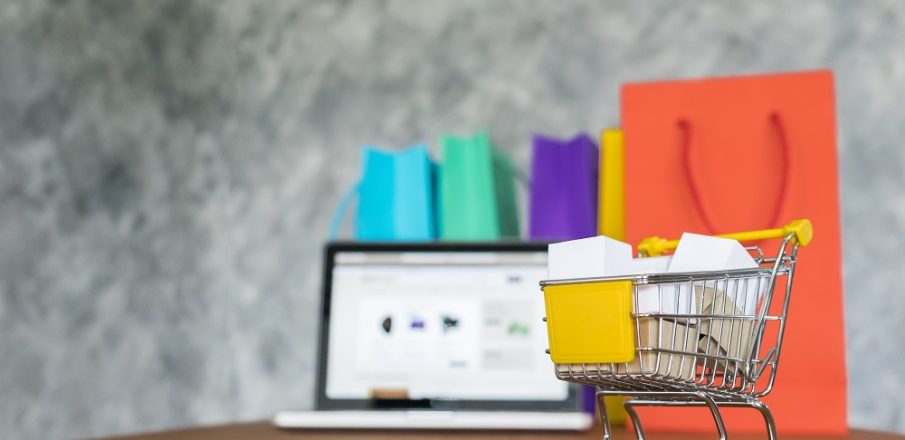 Miniature d’un e-commerce en refonte: un chariot de shopping devant un ordinateur portable et des sacs colorés, illustration d’une refonte site e-commerce prestashop.